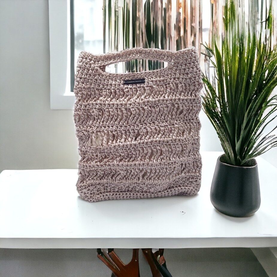 Sac ajouré crocheté en ficelle polypropylène de couleur rose irisé.